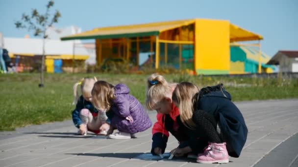 Quatre cousines amicales dessinent avec des crayons sur le trottoir dans un parc municipal — Video