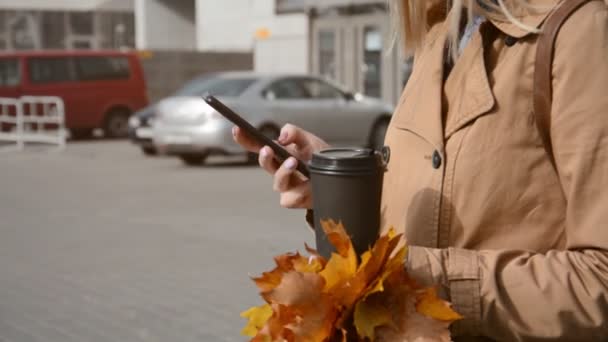 Крупный план деловой женщины, использующей черный смартфон и держащей бумажную чашку кофе — стоковое видео