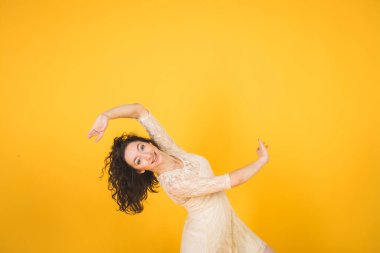 Sarı stüdyo arka planında dans eden zarif klasik balerin.