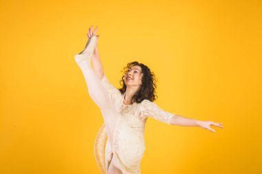 Sarı stüdyo arka planında dans eden zarif klasik balerin.