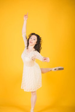 Sarı stüdyo arka planında dans eden zarif klasik balerin.