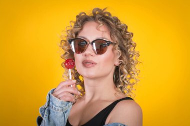 Sarı Arkaplan Karşısında Şeker Kız Lolipopu Tutuyor