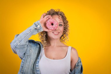 Mutlu gülümseyen güzel kız yüzü donutlu, sarı arka planlı
