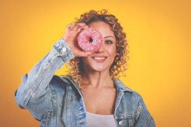 Mutlu gülümseyen güzel kız yüzü donutlu, sarı arka planlı