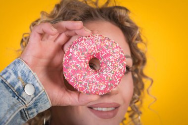 Mutlu gülümseyen güzel kız yüzü donutlu, sarı arka planlı