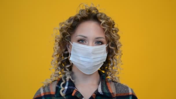Красива дівчина обличчям з кучерявим волоссям в захисній медичній масці — стокове відео