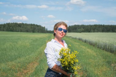 Güzel kız sıcak bir günde tarlada yürür.