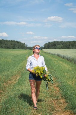 Güzel kız sıcak bir günde tarlada yürür.