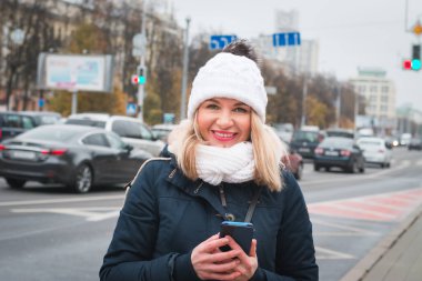 Şehir caddesinde elinde telefon olan güzel bir kız.