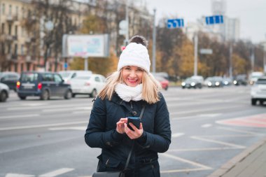 Şehir caddesinde elinde telefon olan güzel bir kız.
