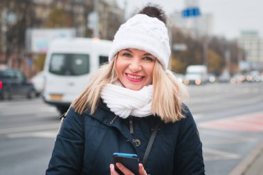Şehir caddesinde elinde telefon olan güzel bir kız.