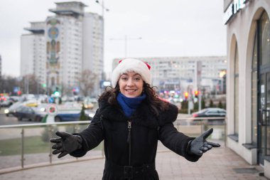 Şehir caddesinde Noel Baba şapkalı güzel bir kızın portresi.