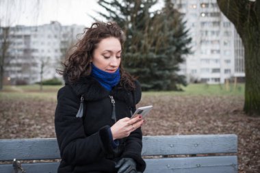 Sıcak giysiler içinde güzel bir kız bulutlu bir kış gününde şehrinin etrafında yürüyor.