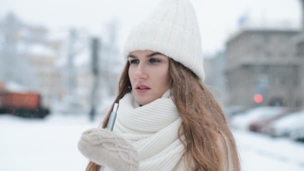Winter portret van een mooi meisje die rookt een elektronische sigaret op een besneeuwde straat — Stockvideo