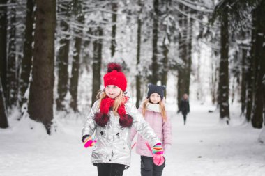 Kış ormanında oynayan iki küçük kız.