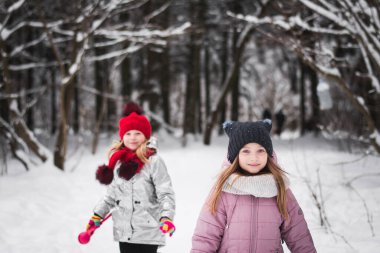 Kış ormanında oynayan iki küçük kız.