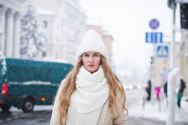 Güzel ve şık bir kız mankeni kışın şehir sokaklarında bir fotoğrafçıya poz veriyor.
