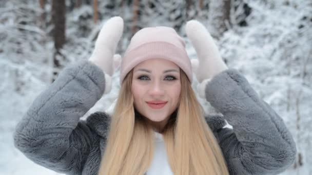 Retrato de una hermosa niña en un sombrero rosa en invierno en un bosque cubierto de nieve — Vídeos de Stock