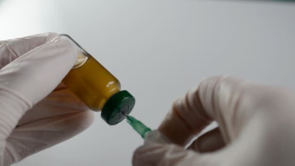 Врачи держат в руках шприц и коричневую бутылку вакцины в больнице. — стоковое видео