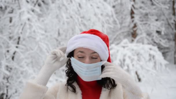 코로나 바이러스로부터 자신을 보호하기 위해 얼굴에 보호용 마스크를 쓴 아름다운 소녀의 크리스마스 겨울 초상화 — 비디오