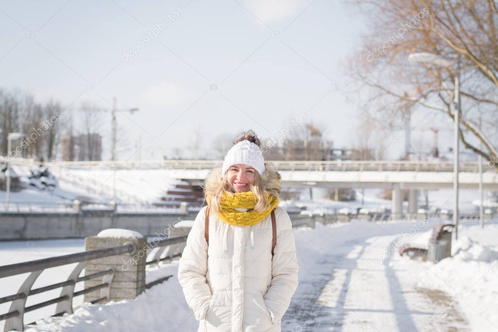 Beautiful blonde girl in white clothes in winter on a city street