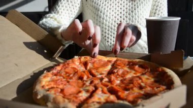 Salamlı bir dilim pizza ve kadın eli.