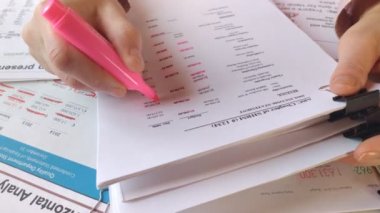 Finansal bilgilerle dolu bir kağıt parçasına pembe kalemle notlar yazar.