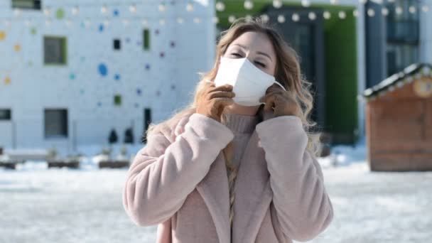 Gyönyörű elegáns orosz lány modell Szibériából áll egy havas utcán télen, és visel védő maszkot — Stock videók