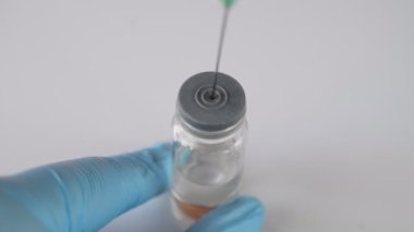 Doktorun ellerini mavi ile kapat koruyucu eldivenler aşıyı şişeden şırıngaya doldurur.