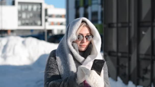 Hermosa modelo de chica rusa de Siberia sostiene un teléfono en sus manos y escribe un mensaje — Vídeo de stock