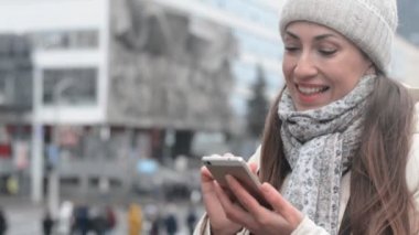 Gülen surat, şehir merkezinde telefon kullanan genç bir kadın.