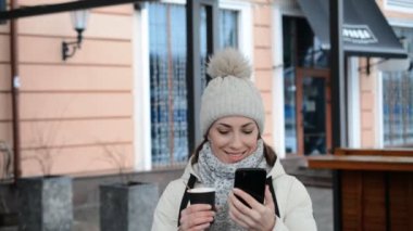 Akıllı telefon kullanan ve kahve içen kadın.