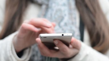 Kafkasyalı genç iş kadınının ellerinde akıllı telefonu kapatın ve ekranda tıklayıp kaydırın
