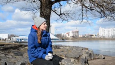 Yalnız kız öğrenci ya da hippi bir fincan kahveyle parkta oturuyor.