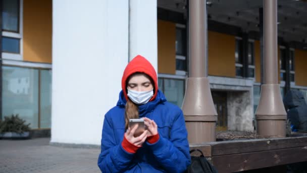 Καυκάσια νεαρή γυναίκα που φοράει προστατευτική μάσκα προσώπου και μιλάει με φίλους από smartphone — Αρχείο Βίντεο