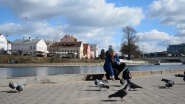 Şehirde güvercinleri besleyen bir kız.