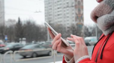 Kış şehrinde sokakta duran akıllı telefondan mesajlaşan kadınların ellerini kapat.