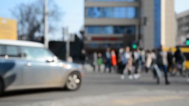 Tanımlanamayan kalabalık yeşil ışıkta geniş yolu geçiyor.