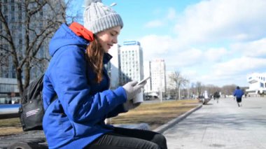 Baharda hippi bir kız şehrin sokaklarında bir bankta oturur kahve içer ve telefonda arkadaşlarıyla sohbet eder.
