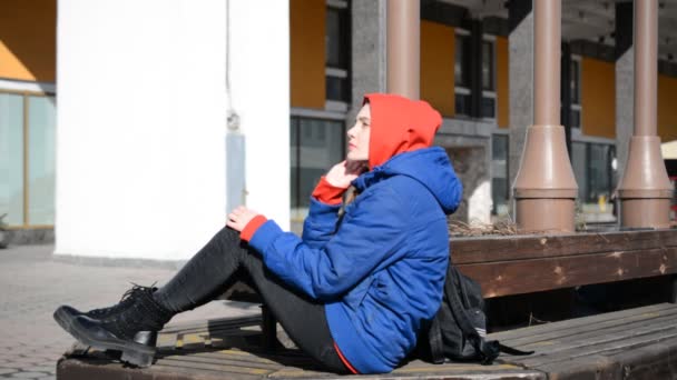 Ledsen hipster flicka gråter på en bänk på en stad — Stockvideo