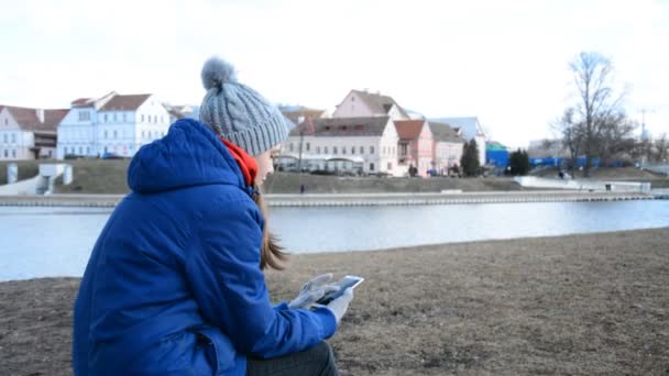 Навесні або восени на задньому плані дівчина пише повідомлення по телефону в міському парку одного європейського міста. — стокове відео