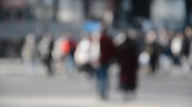 Arka planda yürüyen isimsiz bir kalabalık.