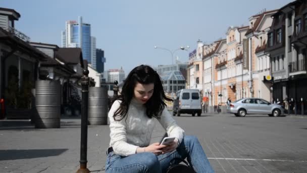 Piękna hipsterka siedzi na ulicy swojego miasta i komunikuje się online — Wideo stockowe