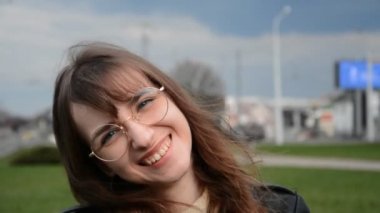 Gözlüklü genç iş kadını kameraya bakıyor.