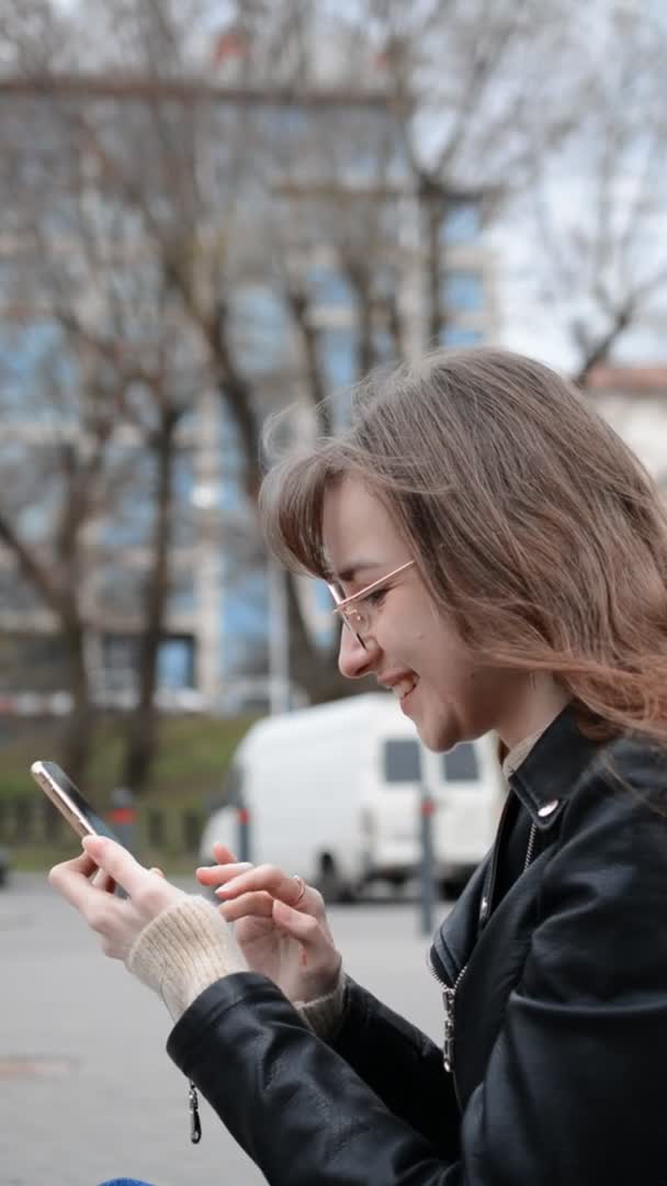 Profil eines Mädchens mit Smartphone auf der Straße der Stadt — Stockvideo