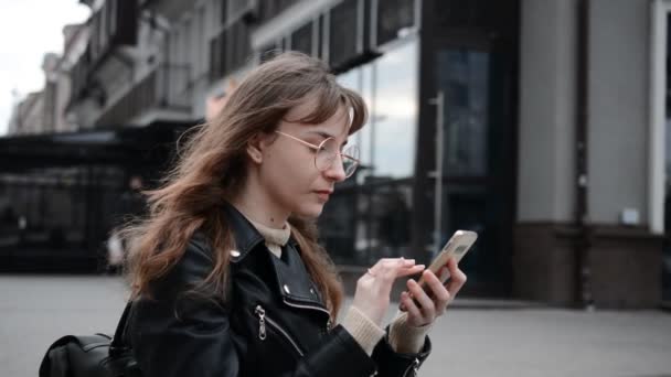 Красива дівчина студент пише з рюкзаком пише повідомлення по телефону — стокове відео