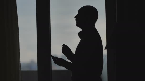 Silhouette of a business man who writes an online message in slow motion near the window — Stock Video