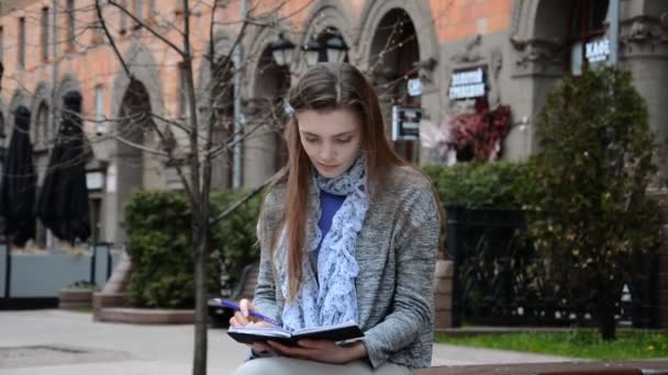 Joven mujer caucásica estudiante haciendo notas en el libro — Vídeo de stock