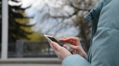 Yakın plan genç iş kadınlarının elleri dokunmatik ekranlı cep telefonlarını tutuyor.