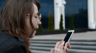 Gözlüklü ve arkadaşlarıyla mesajlaşan genç bir kızın yan görüntüsü